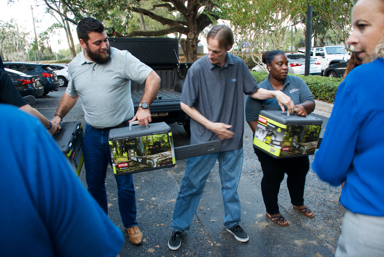 Health Insurance Innovations employees passing chainsaws to the supply truck for victims of Hurricane Michael